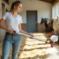 Frau sprüht mit einem Handsprühgerät RevestoPur® auf Heu im Pferdestall, um Staub und Sporen in der Stallluft zu binden.